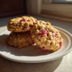 A stack of three freshly baked Strawberry Oatmeal Breakfast Cookies featuring visible oats and bright red strawberry pieces.