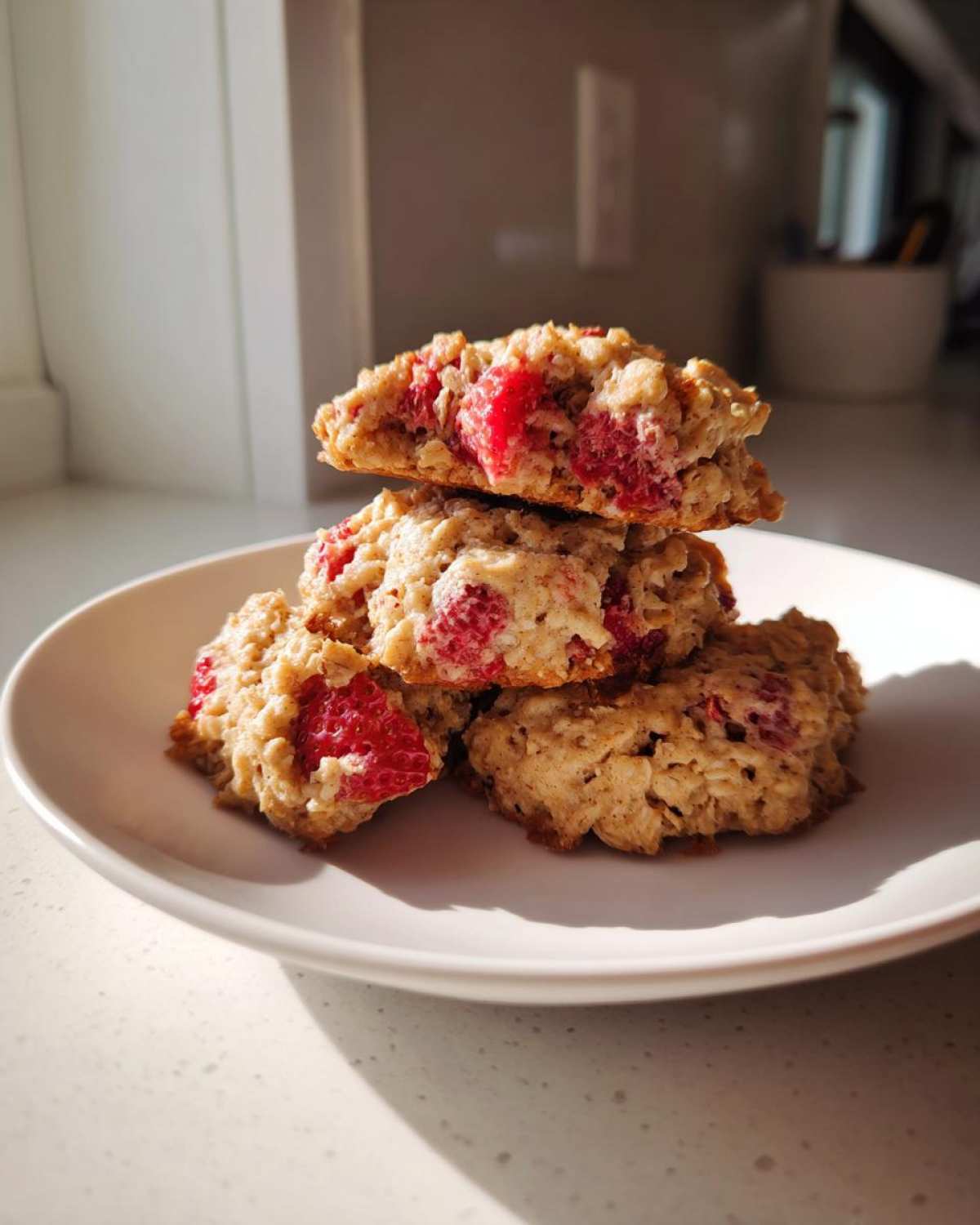 A stack of four soft Strawberry Oatmeal Breakfast Cookies with visible oats and bright red strawberry chunks.