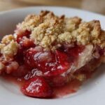 Close-up of a serving of warm Strawberry Rhubarb Crisp showing juicy fruit filling and golden crumble topping.