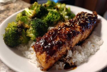 A close-up of a Teriyaki Salmon Rice Bowls serving featuring glazed salmon over white rice and roasted broccoli.