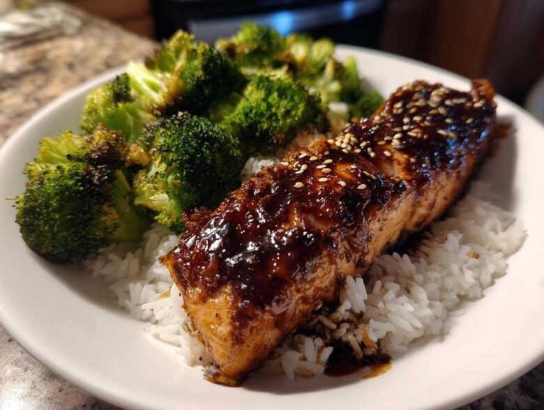 A close-up of a Teriyaki Salmon Rice Bowls serving featuring glazed salmon over white rice and roasted broccoli.
