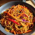 Close-up of vibrant Thai Peanut Noodles with crunchy julienned carrots, red peppers, and purple cabbage.