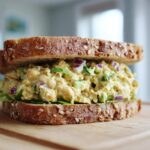 Close-up of a hearty Vegan Chickpea Salad Sandwich made with whole grain bread, creamy filling, red onion, and lettuce.
