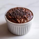 Close-up of rich Vegan Chocolate Chia Pudding topped with extra chia seeds in a white ramekin.