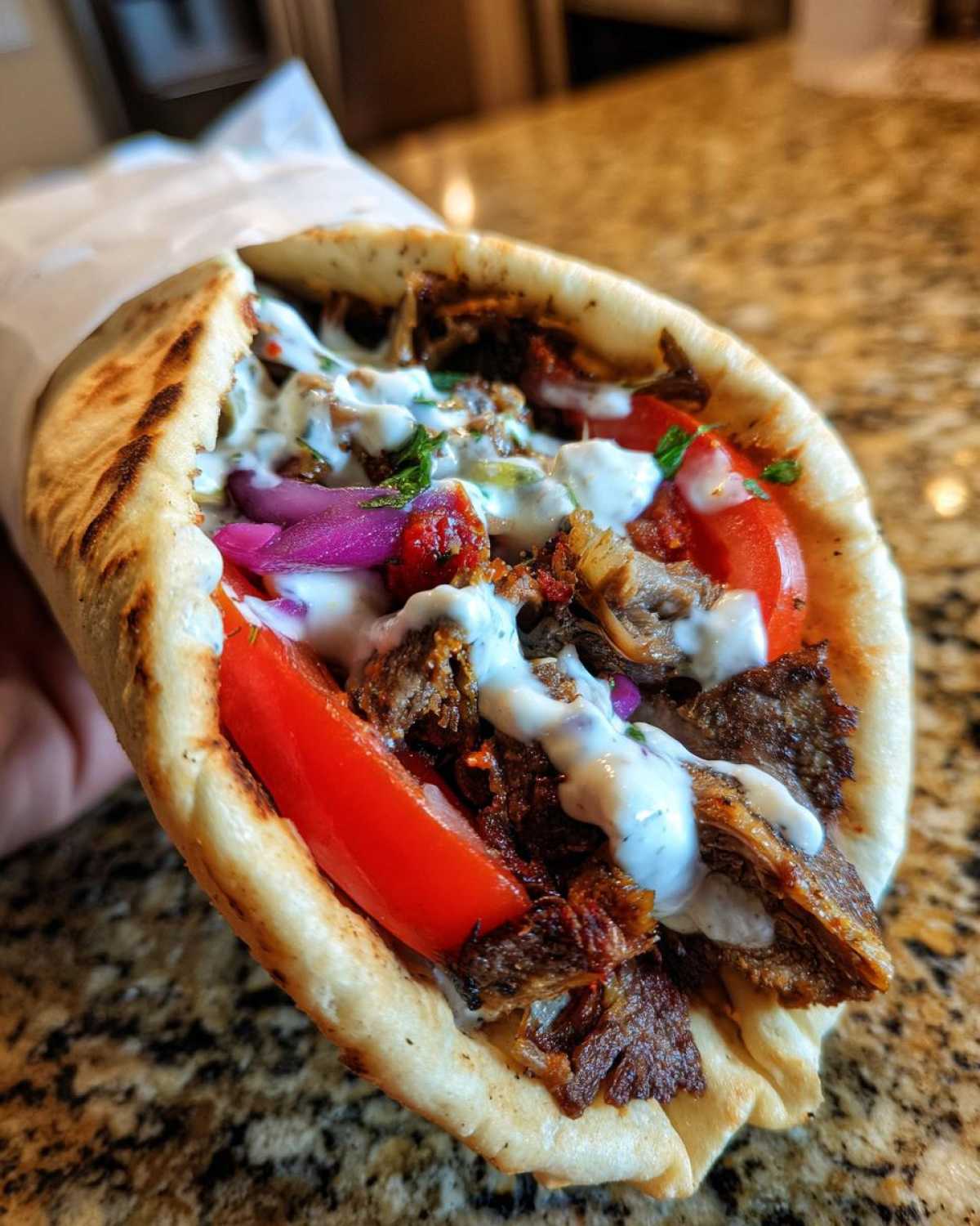 Close-up of a delicious Vegan Mushroom Shawarma wrapped in pita bread with white sauce and fresh vegetables