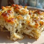 A serving of Cheesy Chicken Alfredo Bake with Mozzarella showing a dramatic cheese pull and golden-brown top.