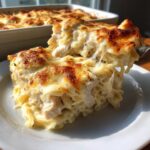 A serving of Cheesy Chicken Alfredo Bake with Mozzarella being lifted, showing melted, stringy cheese and chunks of chicken.