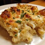 A close-up of a serving of Cheesy Chicken Alfredo Pasta Bake with Mozzarella, showing a golden-brown, bubbly cheese crust.