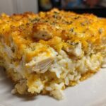 Close-up of a serving of Cheesy Chicken and Rice Bake with Golden Top, showing rice, chicken chunks, and melted cheddar.