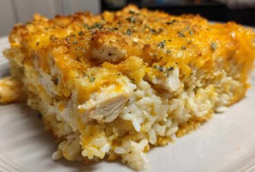 Close-up of a serving of Cheesy Chicken and Rice Bake with Golden Top, showing rice, chicken chunks, and melted cheddar.