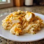 A close-up serving of Cheesy Chicken and Rice Skillet with Cream Sauce, topped with melted cheddar and parsley.