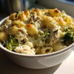 A close-up of a serving of Cheesy Chicken and Broccoli Pasta Bake topped with melted, golden-brown cheese.