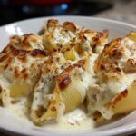 Close-up of baked Cheesy Chicken Stuffed Pasta shells covered in melted, browned cheese and creamy sauce.