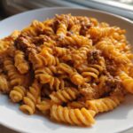 A close-up of Cheesy Ground Beef Pasta with Creamy Sauce featuring rotini pasta coated in an orange sauce with visible ground beef.