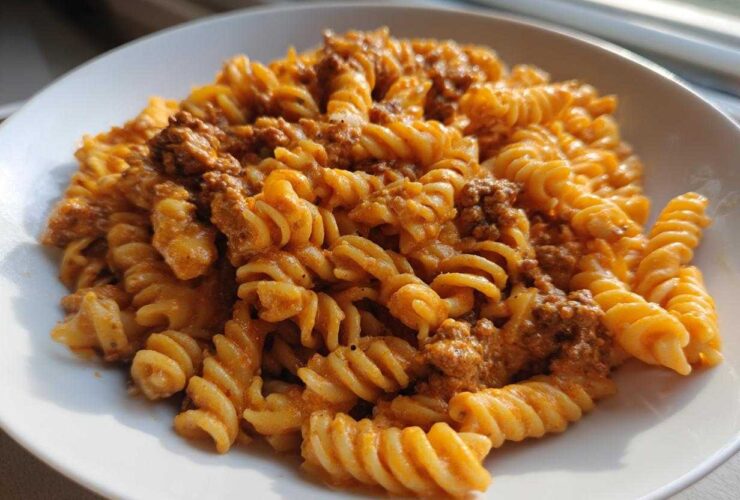 A close-up of Cheesy Ground Beef Pasta with Creamy Sauce featuring rotini pasta coated in an orange sauce with visible ground beef.