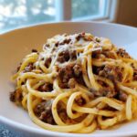 A close-up of Cheesy Ground Beef Pasta with Garlic Cream Sauce, featuring thick noodles coated in sauce and topped with melted cheese.