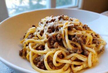 A close-up of Cheesy Ground Beef Pasta with Garlic Cream Sauce, featuring thick noodles coated in sauce and topped with melted cheese.
