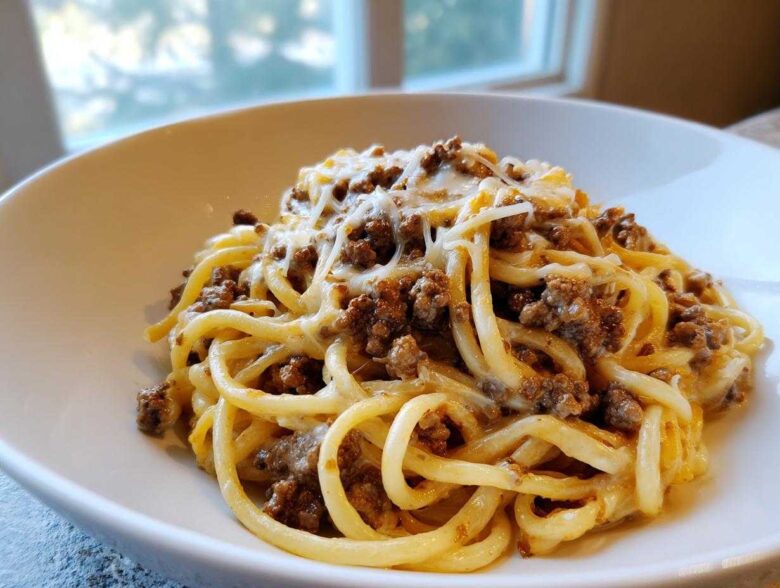 A close-up of Cheesy Ground Beef Pasta with Garlic Cream Sauce, featuring thick noodles coated in sauce and topped with melted cheese.