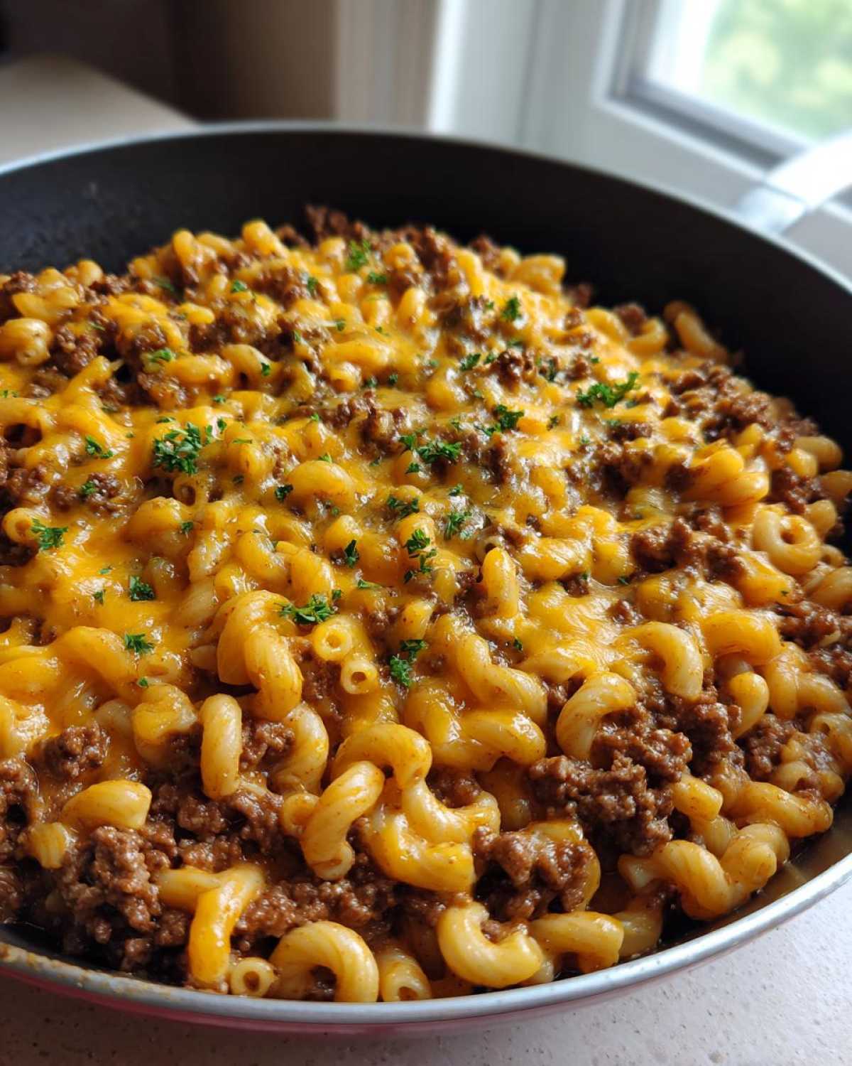 Close-up of a Cheesy Ground Beef Pasta Skillet with elbow macaroni, seasoned ground beef, and melted cheddar cheese.