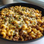 A close-up of a Cheesy Ground Beef Pasta Skillet featuring elbow macaroni, ground beef, and melted cheddar and mozzarella cheese.
