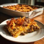 A hearty slice of Cheesy Ground Beef Queso Bake Comfort Dish topped with melted cheese and tortilla chips.