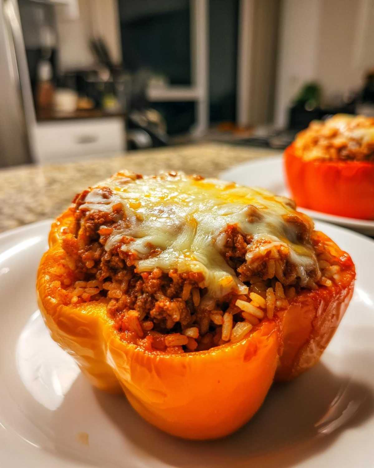 Close-up of a bright orange Cheesy Ground Beef Stuffed Peppers with Rice, topped with melted mozzarella cheese.