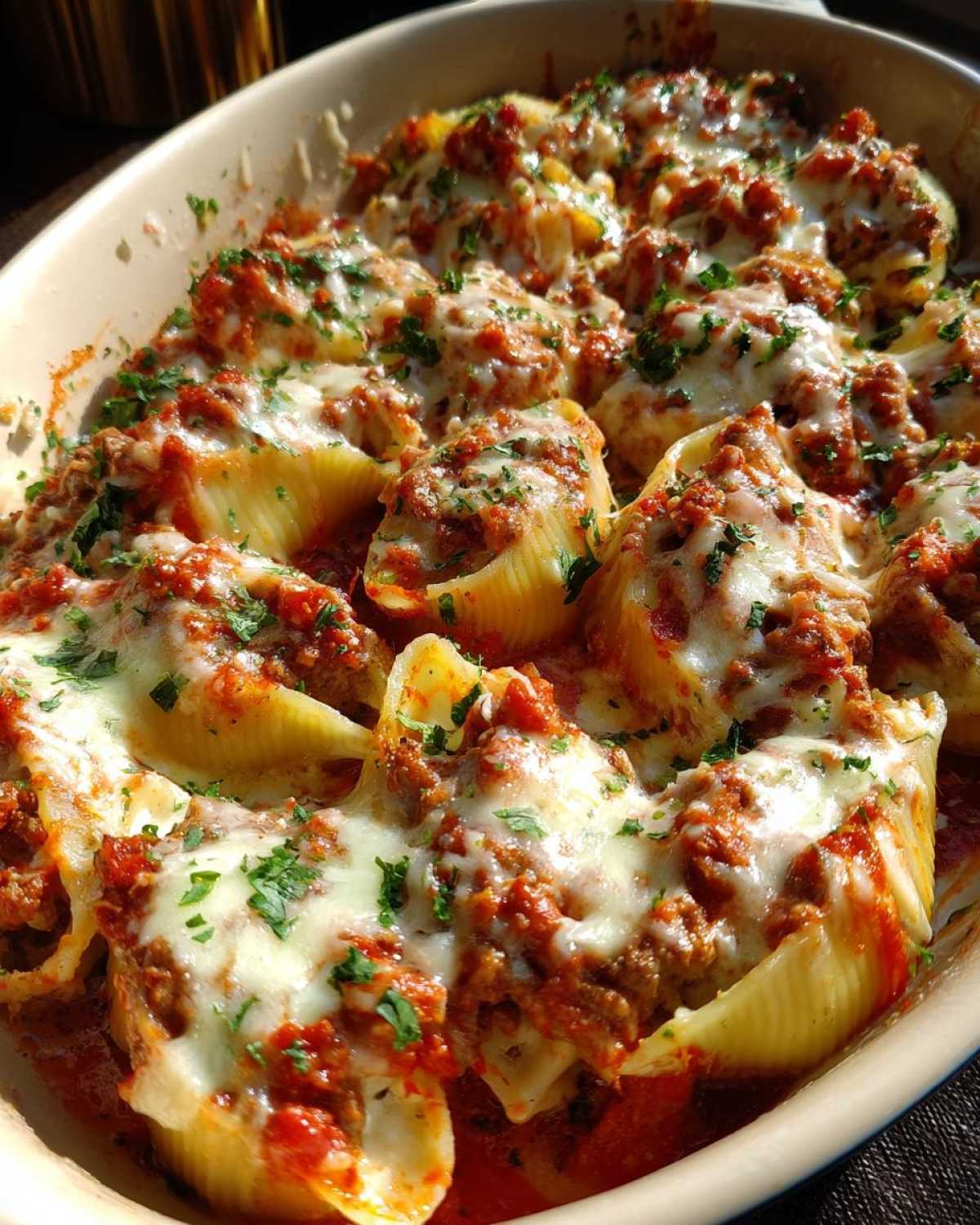 Close-up of baked Cheesy Ground Beef Stuffed Shells with melted mozzarella and parsley garnish.