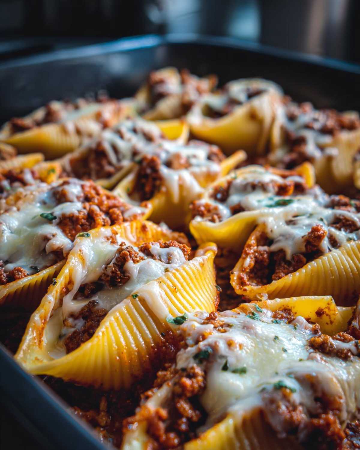 Close-up of baked Cheesy Ground Beef Stuffed Shells topped with melted mozzarella cheese.