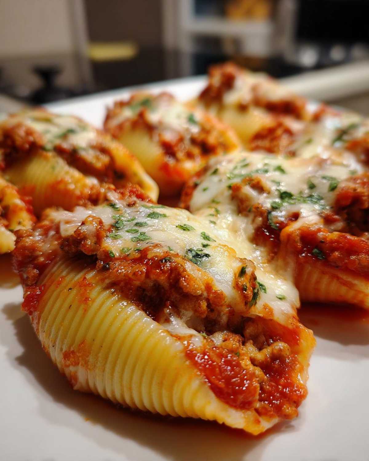 A close-up of baked jumbo pasta shells filled with ground beef, covered in marinara sauce and melted mozzarella cheese, part of the Cheesy Ground Beef Stuffed Shells Easy Bake.