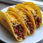 Four crispy hard-shell Cheesy Ground Beef Tacos filled with seasoned meat, creamy sauce, and shredded cheddar and Monterey Jack cheese.