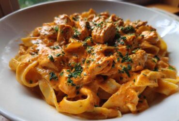 Close-up of Creamy Cajun Chicken Pasta featuring fettuccine noodles, chunks of chicken, and a rich orange sauce, garnished with parsley.