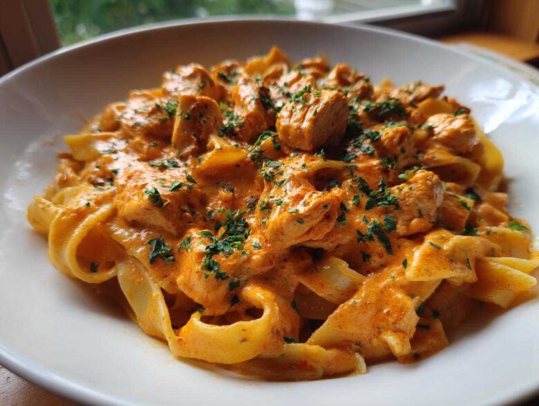 Close-up of Creamy Cajun Chicken Pasta featuring fettuccine noodles, chunks of chicken, and a rich orange sauce, garnished with parsley.