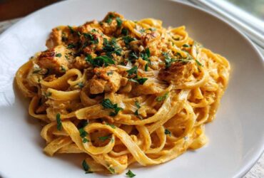 A close-up of a serving of rich Creamy Cajun Chicken Pasta with Garlic Flavor, topped with fresh parsley.