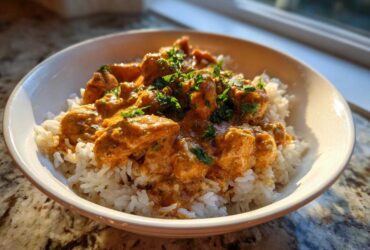 A bowl of Creamy Cajun Chicken Skillet with Rice topped with fresh parsley, lit by sunlight.