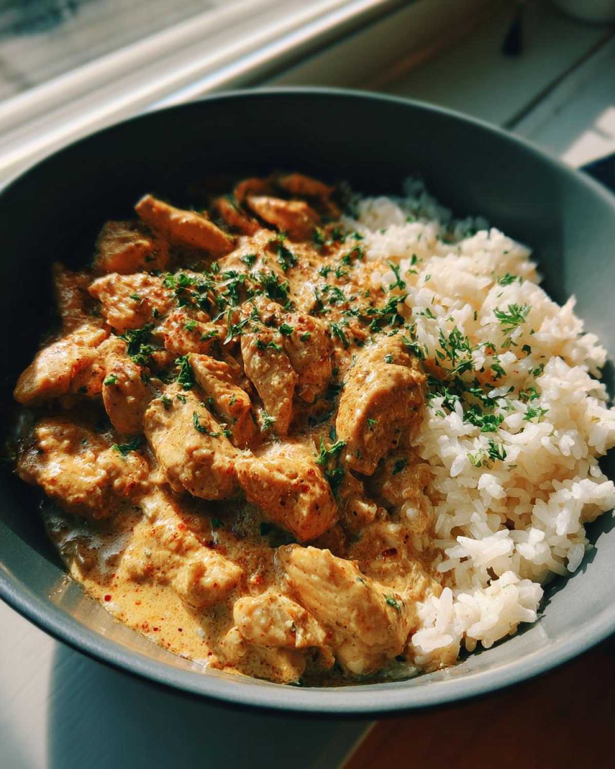 Close-up of Creamy Cajun Chicken Skillet with Rice served in a dark bowl, garnished with parsley.