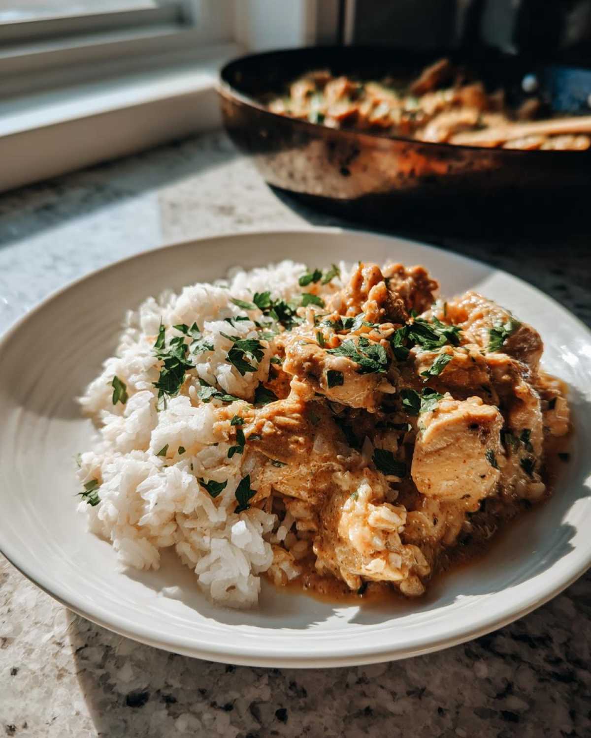 A plate featuring creamy Cajun chicken skillet served alongside fluffy white rice and garnished with fresh parsley.