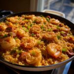 Close-up of a skillet filled with vibrant Creamy Cajun Shrimp and Rice Skillet, topped with large shrimp and green onions.