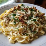 A close-up of creamy Garlic Butter Chicken Pasta with Parmesan, topped with shredded chicken and fresh parsley.
