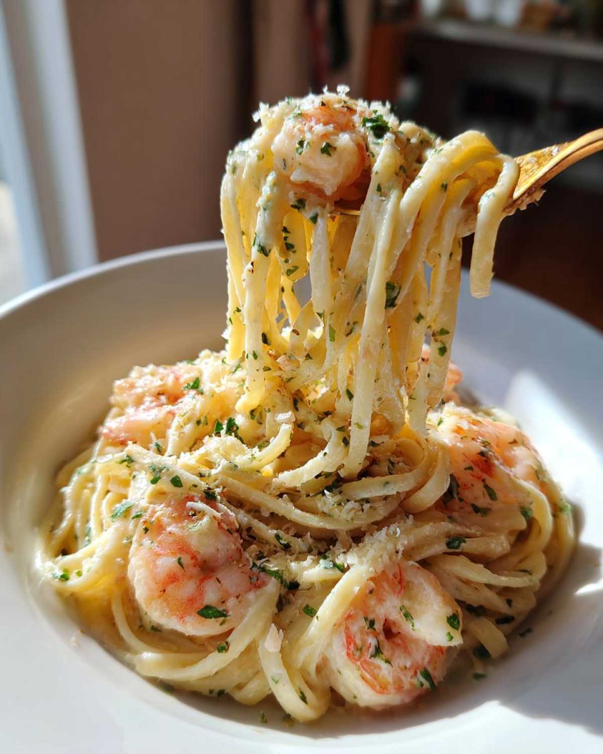 A fork lifts a twirl of creamy Garlic Butter Shrimp Pasta with visible shrimp, parsley, and grated cheese.