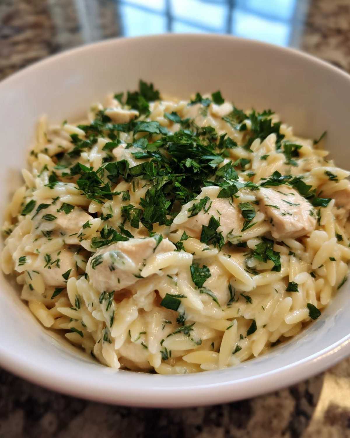 Close-up of Creamy Lemon Chicken Orzo with chunks of chicken and topped with fresh chopped parsley.