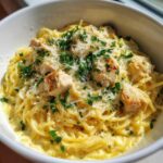 Close-up of a white bowl filled with Creamy Lemon Chicken Pasta with Parmesan, topped with parsley.