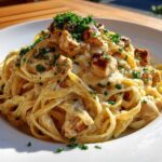 A close-up of a serving of Creamy Lemon Garlic Pasta with Chicken, topped with fresh parsley.
