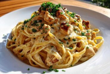 A close-up of a serving of Creamy Lemon Garlic Pasta with Chicken, topped with fresh parsley.
