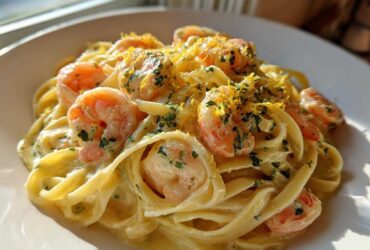 A close-up of rich Creamy Lemon Garlic Shrimp Pasta tossed in a bright sauce and topped with lemon zest and parsley.