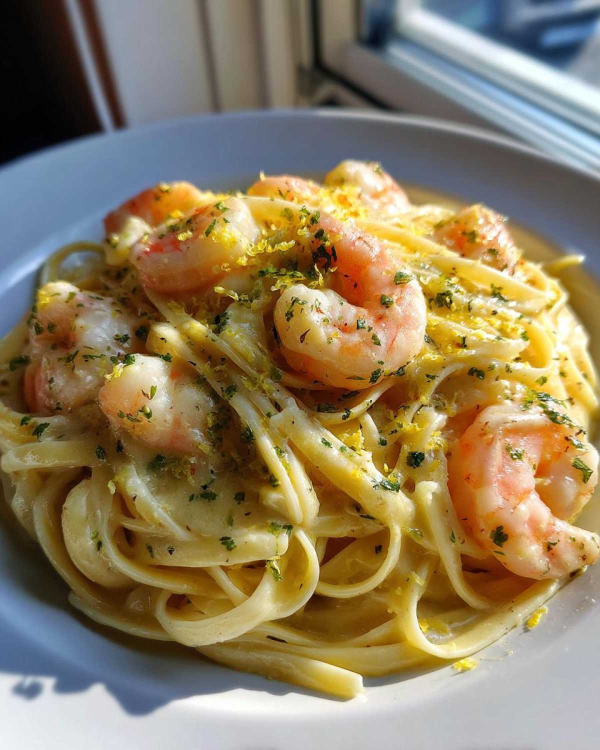 Close-up of Creamy Lemon Garlic Shrimp Pasta topped with bright lemon zest and fresh parsley.