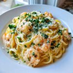 A close-up of a white bowl filled with Creamy Lemon Shrimp Pasta with Garlic Sauce, topped with Parmesan and parsley.