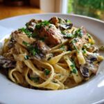 A close-up of a serving of Creamy Mushroom Chicken Pasta with Garlic Sauce, topped with fresh parsley.