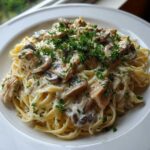 A close-up of a serving of Creamy Mushroom Chicken Pasta with Parmesan, topped with fresh parsley.