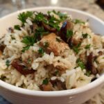Close-up of a white bowl filled with Creamy Mushroom Chicken and Rice Skillet, garnished with fresh parsley.