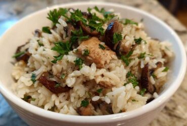 Close-up of a white bowl filled with Creamy Mushroom Chicken and Rice Skillet, garnished with fresh parsley.
